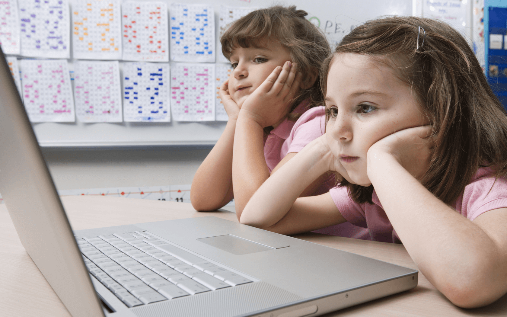 2人の欧米人の子どもが学校でパソコンに表示された電子書籍を読んでいるイメージ